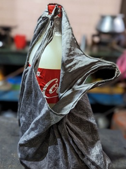 Image shows a bottle of coke filled with locally produced unregulated alcohol, which is often produced from fermented or distilled grain.